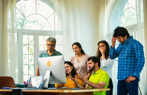 Hindistanlı Asyalı genç iş adamları yeni ortakları rahat ofislerinde bilgisayar üzerinde çok önemli bir proje üzerinde çalışıyorlar. Beklenmedik bir başarısızlık ya da gerilemeyle karşılaştıklarında birden hayal kırıklığına uğradılar, üzüldüler, üzüldüler.