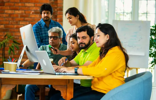 Hintli Asyalı genç iş adamları veya girişim ortakları önemli bir projede işbirliği yapıyor, bilgisayarda yoğun bir şekilde çalışıyor, tartışmalara katılan her takım üyesi, karar verme mekanizması