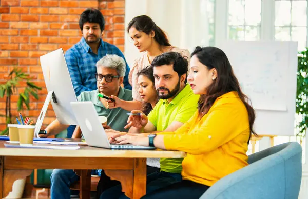 Hintli Asyalı genç iş adamları veya girişim ortakları önemli bir projede işbirliği yapıyor, bilgisayarda yoğun bir şekilde çalışıyor, tartışmalara katılan her takım üyesi, karar verme mekanizması