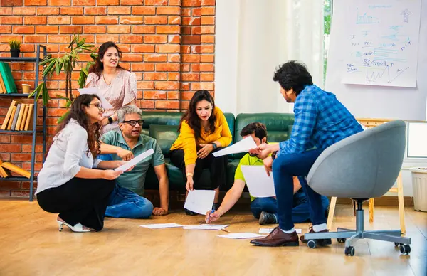 Hindistanlı Asyalı genç iş ortakları yeni ortaklar belgelerle önemli projeler planlarken modern, samimi, katılımcı ve takım çalışması olan ofiste birlikte oturuyorlar.