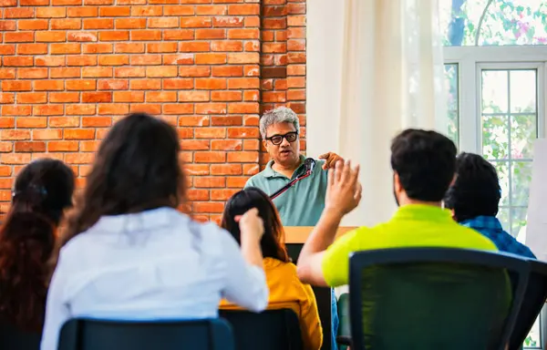 Hintli Asyalı yaşam koçu, profesyonel akıl hocası konferansta bir grup genç girişimciye iş büyümesi girişimciliği hakkında ilham verici bir konuşma yapıyor, mikrofonla podyumda güvenle konuşuyor.