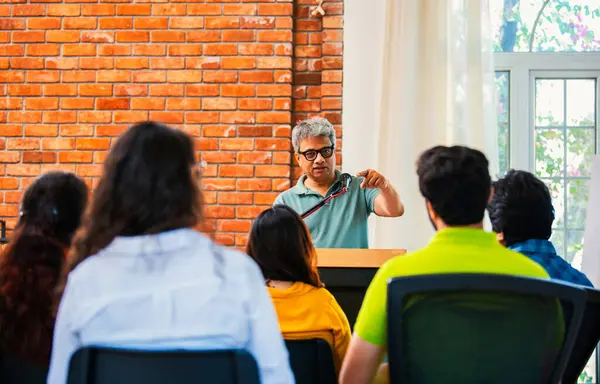 Hintli Asyalı yaşam koçu, profesyonel akıl hocası konferansta bir grup genç girişimciye iş büyümesi girişimciliği hakkında ilham verici bir konuşma yapıyor, mikrofonla podyumda güvenle konuşuyor.