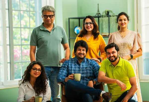 Genç girişimcilerden oluşan Hint Asya dinamik ekibi modern yaratıcı ofiste başarıyı kutluyor. Kameraya, takım çalışmasına, lidere gülümseyen iş adamlarına güveniyorlar.