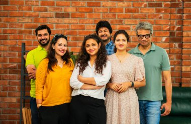 Hint Asya dinamik girişim ekibi genç girişimcilerden oluşan akıllı girişimciler modern yaratıcı ofiste bir arada duruyorlar kameraya, takım çalışmasına, lidere gülümseyen iş adamlarına güveniyorlar.