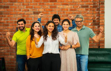 Genç girişimcilerden oluşan Hint Asya dinamik ekibi modern yaratıcı ofiste başarıyı kutluyor. Kameraya, takım çalışmasına, lidere gülümseyen iş adamlarına güveniyorlar.