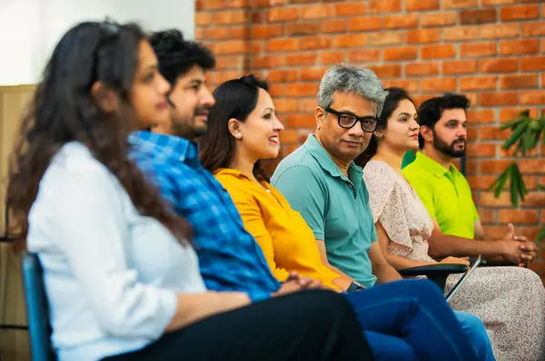 Hintli Asyalı genç iş adamları ya da girişim ekibi modern bir konferans salonunda kurumsal bir konuşma, liderlik dersi, eğitim oturumu için toplanıyor.