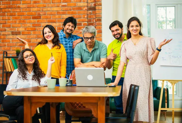 Hintli Asyalı genç iş adamları konferans masasının yanında yaratıcı bir çalışma ortamındaki başarıyı kutlamak için bir araya geldiler.