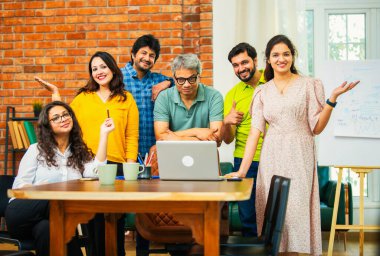 Hintli Asyalı genç iş adamları konferans masasının yanında yaratıcı bir çalışma ortamındaki başarıyı kutlamak için bir araya geldiler.