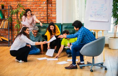Hindistanlı Asyalı genç iş ortakları yeni ortaklar belgelerle önemli projeler planlarken modern, samimi, katılımcı ve takım çalışması olan ofiste birlikte oturuyorlar.