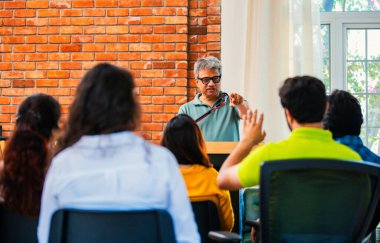 Hintli Asyalı yaşam koçu, profesyonel akıl hocası konferansta bir grup genç girişimciye iş büyümesi girişimciliği hakkında ilham verici bir konuşma yapıyor, mikrofonla podyumda güvenle konuşuyor.