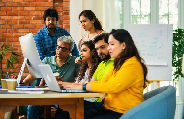 Hintli Asyalı genç iş adamları veya girişim ortakları önemli bir projede işbirliği yapıyor, bilgisayarda yoğun bir şekilde çalışıyor, tartışmalara katılan her takım üyesi, karar verme mekanizması