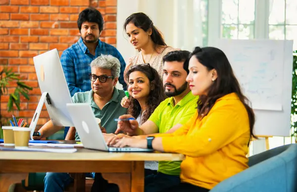 Hintli Asyalı genç iş adamları veya girişim ortakları önemli bir projede işbirliği yapıyor, bilgisayarda yoğun bir şekilde çalışıyor, tartışmalara katılan her takım üyesi, karar verme mekanizması