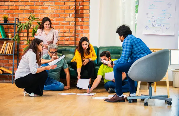 Hindistanlı Asyalı genç iş ortakları yeni ortaklar belgelerle önemli projeler planlarken modern, samimi, katılımcı ve takım çalışması olan ofiste birlikte oturuyorlar.