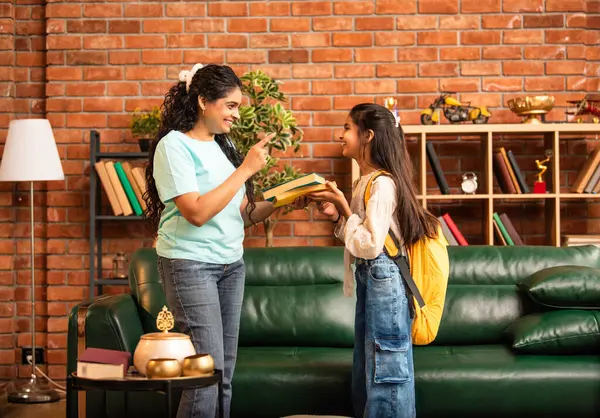 Hintli bir anne, kızının okula gitmesine yardım etmek için kitap paketliyor, okul çantasına beslenme çantası koyuyor, ona sevgiyle sarılıyor ve sıcak bir ev ortamında şefkatle onu uğurluyor.