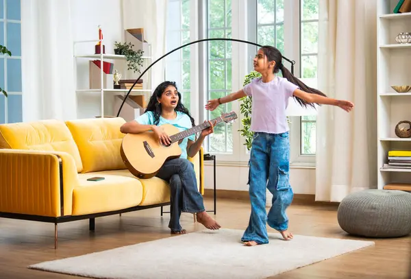 Hint Asyalı genç bir anne akustik gitar çalarken küçük kızı geniş ve modern bir evde neşeyle dans ediyor. Sevgisini gösteriyor, aile bağı kuruyor, eğleniyor ve birlikte zaman geçiriyor.