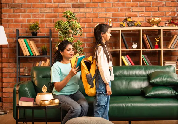 Hintli bir anne, kızının okula gitmesine yardım etmek için kitap paketliyor, okul çantasına beslenme çantası koyuyor, ona sevgiyle sarılıyor ve sıcak bir ev ortamında şefkatle onu uğurluyor.