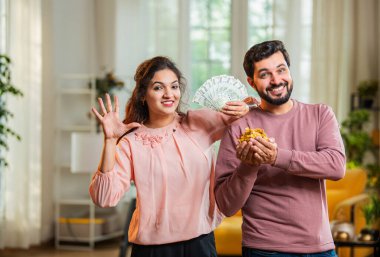 Hintli Asyalı genç koca elinde altın takılar olan kafası karışık bir eş arkadan beliriyor. Rupi hayranı hem başarıyı hem de altın kredi hem de ipotek kavramını kutluyor.