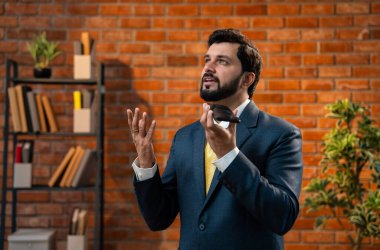 Hoparlörden konuşan Hintli işadamı rahat bir ofiste takım elbise ve kravat takıyor Asyalı CEO ya da sakallı bir şirket çalışanı terasotta tuğlasına karşı akıllı telefon aracılığıyla iletişim kuruyor.