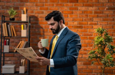 Hintli işadamı, rahat ofisinde kahveyle gazete okuyor. Sakallı resmi takım elbiseli Asyalı bir CEO ya da girişimci günlük iş haberlerine yetişmek için tuğla duvara yaslanıyor.