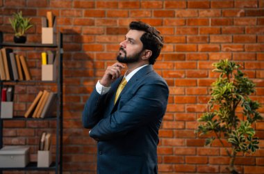 Kafası karışmış Hintli genç işadamı ya da CEO 'nun resmi takım elbiseli, sakallı, düşünceli, düşünceli ya da teras tuğlalı duvarlı sıcak bir ofiste çözüm bulan portresi.