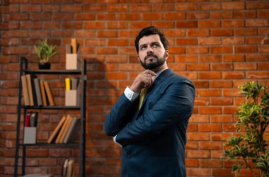 Kafası karışmış Hintli genç işadamı ya da CEO 'nun resmi takım elbiseli, sakallı, düşünceli, düşünceli ya da teras tuğlalı duvarlı sıcak bir ofiste çözüm bulan portresi.