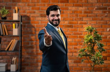 Mutlu Hintli Asyalı genç işadamı, CEO ya da girişimci resmi kurumsal kıyafetli, sakallı, güvenli bir şekilde kameraya yaklaşıp rahat bir ofiste el sıkışmak istiyor.