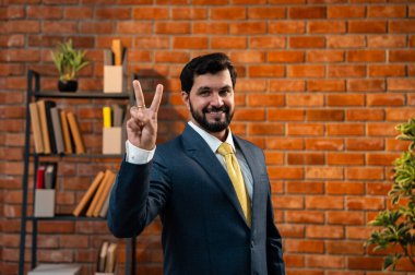 Sayıları gösterirken kendine güvenen parmakları kullanan, resmi kurumsal giyinmiş Hintli Asyalı sakallı ceo işadamı parmaklarını sayarken tuğla duvara karşı samimi bir ofiste duruyor.