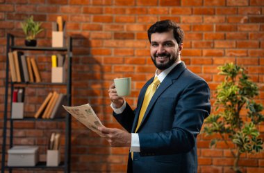 Hintli işadamı, rahat ofisinde kahveyle gazete okuyor. Sakallı resmi takım elbiseli Asyalı bir CEO ya da girişimci günlük iş haberlerine yetişmek için tuğla duvara yaslanıyor.