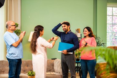 Genç Hintli bir adam iş görüşmesini kırar, üst düzey ebeveynler ve kız kardeşlerle tanışmak için yönetici kıyafetiyle eve döner, aileye sarılır, kutsanmak ister, başarıyı kutlar ve neşeli duygusal anı paylaşır.