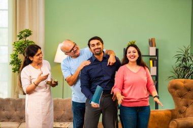 Genç Hintli bir adam iş görüşmesini kırar, üst düzey ebeveynler ve kız kardeşlerle tanışmak için yönetici kıyafetiyle eve döner, aileye sarılır, kutsanmak ister, başarıyı kutlar ve neşeli duygusal anı paylaşır.