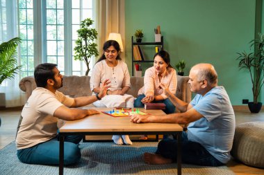 Kapalı alanlarda ludo masası oyunu oynuyorlar, dört kişilik Hint ailesi, yaşlı ebeveynler, genç yetişkin bir çocuk ve kız evdeki modern sıcak oturma odasında birlikte otururken kaliteli vakit geçirmenin keyfini çıkarıyorlar.
