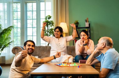 Kapalı alanlarda ludo masası oyunu oynuyorlar, dört kişilik Hint ailesi, yaşlı ebeveynler, genç yetişkin bir çocuk ve kız evdeki modern sıcak oturma odasında birlikte otururken kaliteli vakit geçirmenin keyfini çıkarıyorlar.