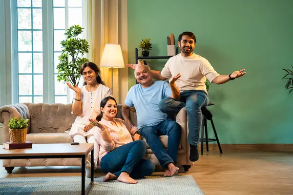 Evde otururken birlikte gülerdik. Yaşlı ebeveynleri ve küçük yetişkin çocukları olan mutlu Hintli aile modern rahat bir oturma odasında eğlenceli sohbetler yapar, kaliteli zaman geçirirdik.