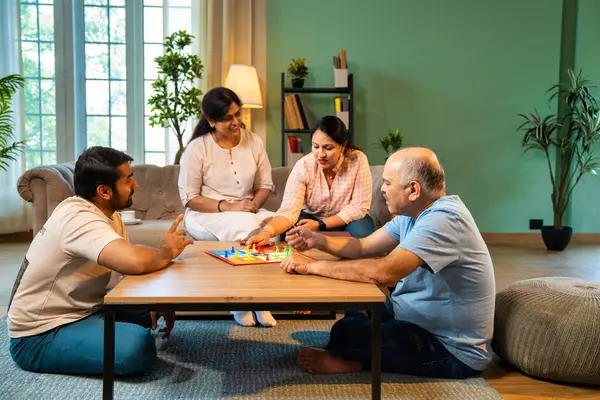 Kapalı alanlarda ludo masası oyunu oynuyorlar, dört kişilik Hint ailesi, yaşlı ebeveynler, genç yetişkin bir çocuk ve kız evdeki modern sıcak oturma odasında birlikte otururken kaliteli vakit geçirmenin keyfini çıkarıyorlar.