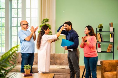 Genç Hintli bir adam iş görüşmesini kırar, üst düzey ebeveynler ve kız kardeşlerle tanışmak için yönetici kıyafetiyle eve döner, aileye sarılır, kutsanmak ister, başarıyı kutlar ve neşeli duygusal anı paylaşır.