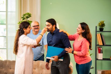 Genç Hintli bir adam iş görüşmesini kırar, üst düzey ebeveynler ve kız kardeşlerle tanışmak için yönetici kıyafetiyle eve döner, aileye sarılır, kutsanmak ister, başarıyı kutlar ve neşeli duygusal anı paylaşır.