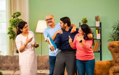 Genç Hintli bir adam iş görüşmesini kırar, üst düzey ebeveynler ve kız kardeşlerle tanışmak için yönetici kıyafetiyle eve döner, aileye sarılır, kutsanmak ister, başarıyı kutlar ve neşeli duygusal anı paylaşır.