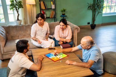 Kapalı alanlarda ludo masası oyunu oynuyorlar, dört kişilik Hint ailesi, yaşlı ebeveynler, genç yetişkin bir çocuk ve kız evdeki modern sıcak oturma odasında birlikte otururken kaliteli vakit geçirmenin keyfini çıkarıyorlar.