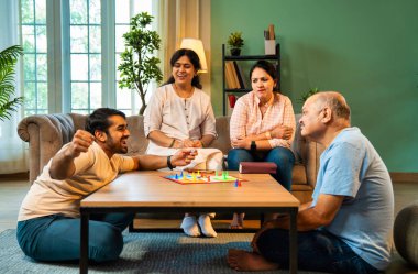 Kapalı alanlarda ludo masası oyunu oynuyorlar, dört kişilik Hint ailesi, yaşlı ebeveynler, genç yetişkin bir çocuk ve kız evdeki modern sıcak oturma odasında birlikte otururken kaliteli vakit geçirmenin keyfini çıkarıyorlar.