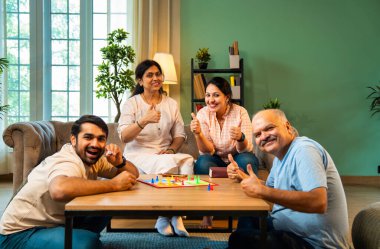 Kapalı alanlarda ludo masası oyunu oynuyorlar, dört kişilik Hint ailesi, yaşlı ebeveynler, genç yetişkin bir çocuk ve kız evdeki modern sıcak oturma odasında birlikte otururken kaliteli vakit geçirmenin keyfini çıkarıyorlar.