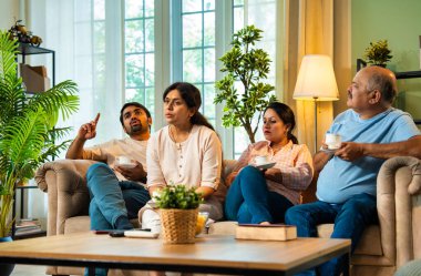 Çay içip önemli konuları tartışıyoruz, Hintli aileler, modern oturma odasındaki rahat koltukta oturan yetişkin çocuklar ve kızlar ciddi aile sohbetleriyle meşguller.