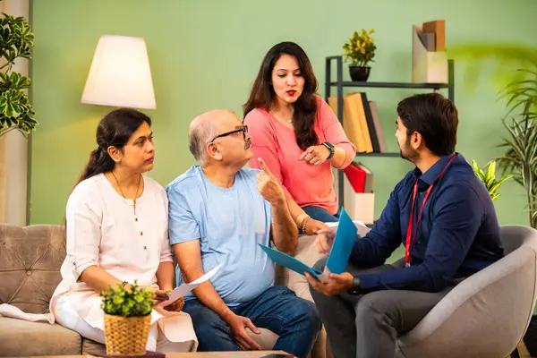 Genç kızı olan Hintli üst düzey bir çift, emlak kredisi veya tasarruf danışmanlığı kavramında resmi giyimde erkek danışman veya banka temsilcisiyle mali evrakları tartışıyor.