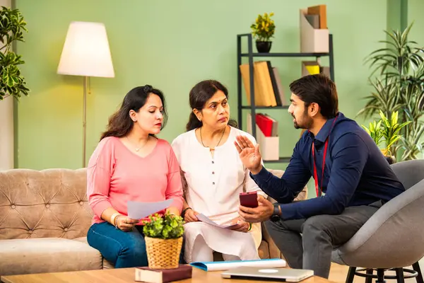 Hintli üst düzey anne ve genç kız, erkek danışman ile finansal planlarını tartışıyor. Detayları dizüstü bilgisayarda gösteriyor. Müşteri toplantısı, danışma, sigorta, ev kredisi sözleşmesi