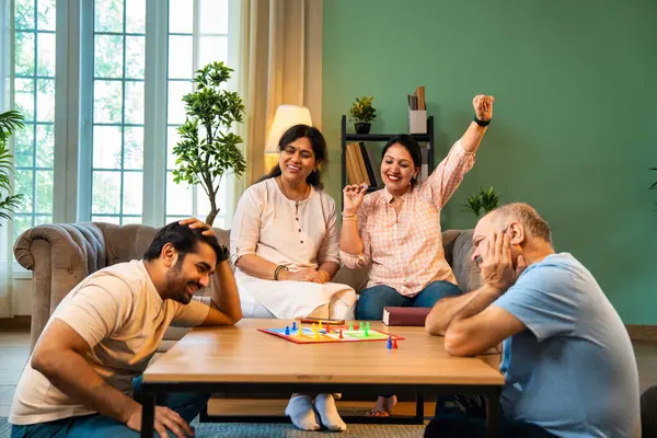 Kapalı alanlarda ludo masası oyunu oynuyorlar, dört kişilik Hint ailesi, yaşlı ebeveynler, genç yetişkin bir çocuk ve kız evdeki modern sıcak oturma odasında birlikte otururken kaliteli vakit geçirmenin keyfini çıkarıyorlar.