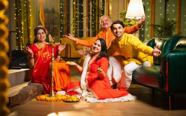 Diwali 'de evde samai diya aydınlatması, Hintli dört kişilik Hint ailesi sari, baba, genç kız ve koca Hindu festivalini neşe ve gelenekle kutlarken birlikte gülümsüyor.