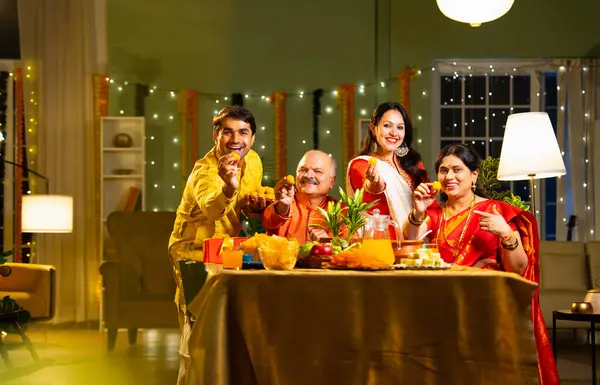 Laddu 'yu kameraya gösteriyoruz, Hintli dört çocuklu Hintli aile. Hindu festivalini kutlayan yetişkin bir aile. Diwali içeride, dekore edilmiş yemek masasında, gülümsüyor ve birlikte eğleniyorlar.
