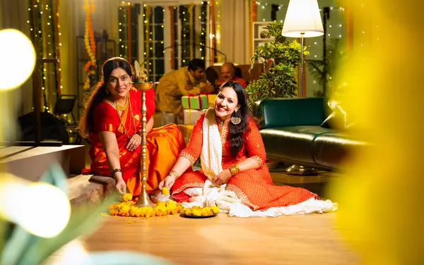 Samai 'nin etrafındaki çiçek Rangoli' sini süsleyen Hintli genç kız geleneksel Hindu kıdemli anne Hint festivali için neşe içinde hazırlanıyor Diwali akşam saatlerinde kapalı bir yerde moda ve renkli tasarım ile kutlama yapıyor.