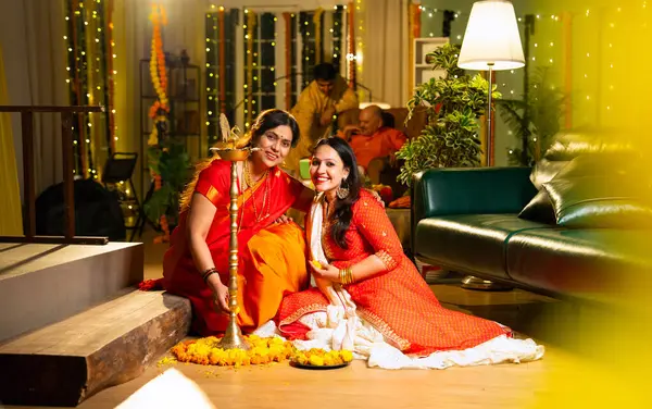 Samai 'nin etrafındaki çiçek Rangoli' sini süsleyen Hintli genç kız geleneksel Hindu kıdemli anne Hint festivali için neşe içinde hazırlanıyor Diwali akşam saatlerinde kapalı bir yerde moda ve renkli tasarım ile kutlama yapıyor.