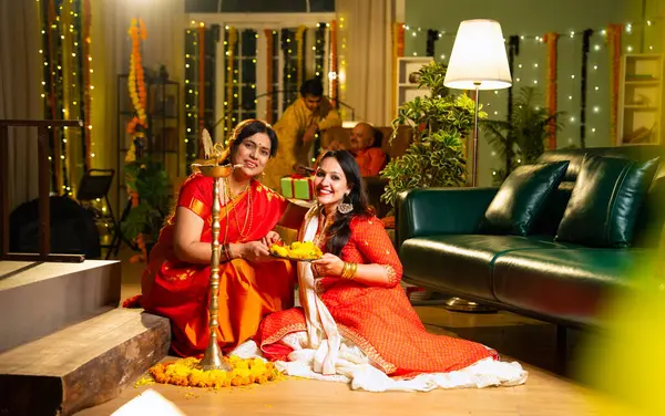 Samai 'nin etrafındaki çiçek Rangoli' sini süsleyen Hintli genç kız geleneksel Hindu kıdemli anne Hint festivali için neşe içinde hazırlanıyor Diwali akşam saatlerinde kapalı bir yerde moda ve renkli tasarım ile kutlama yapıyor.
