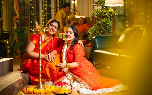 Samai 'nin etrafındaki çiçek Rangoli' sini süsleyen Hintli genç kız geleneksel Hindu kıdemli anne Hint festivali için neşe içinde hazırlanıyor Diwali akşam saatlerinde kapalı bir yerde moda ve renkli tasarım ile kutlama yapıyor.